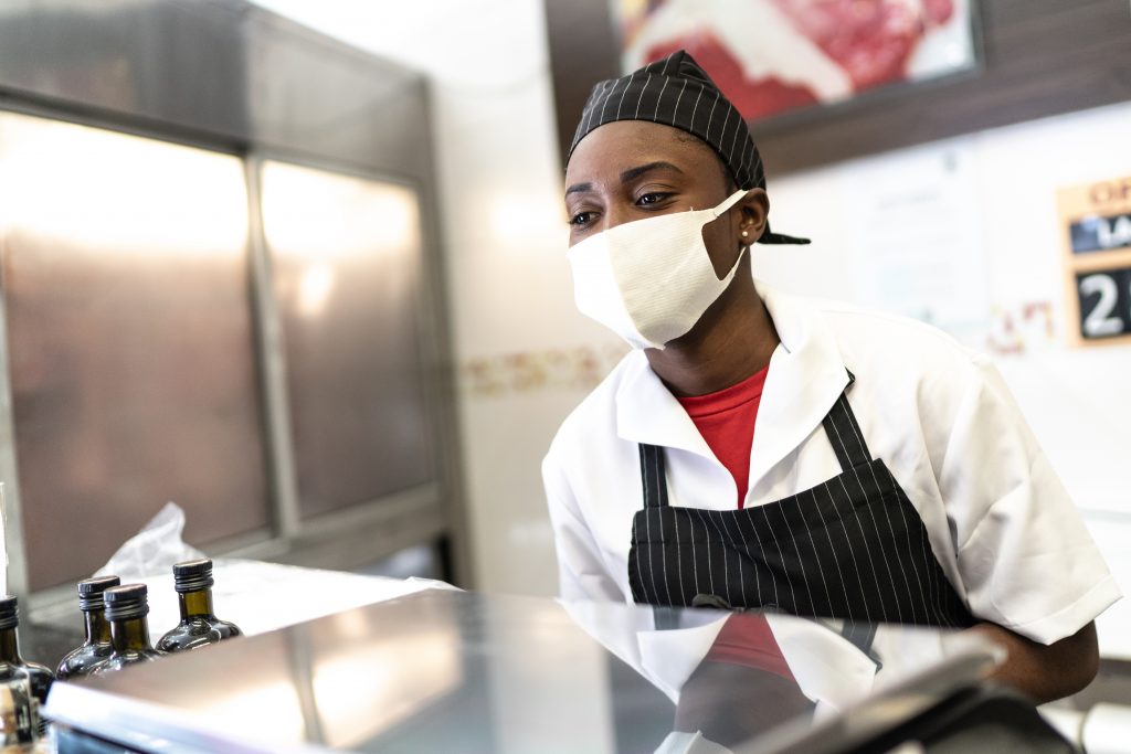 Female butcher talking to customer at grocery store butcher shop