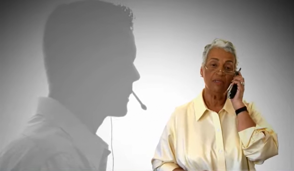 Screenshot of telephone scams video with shadow of a telemarketer hovering above a woman on the phone