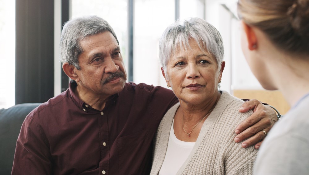 Two older adults speak to a caregiver