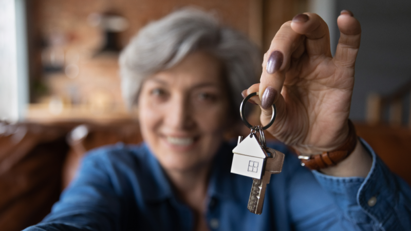 A woman hold up keys with a keychain in the shape of a house