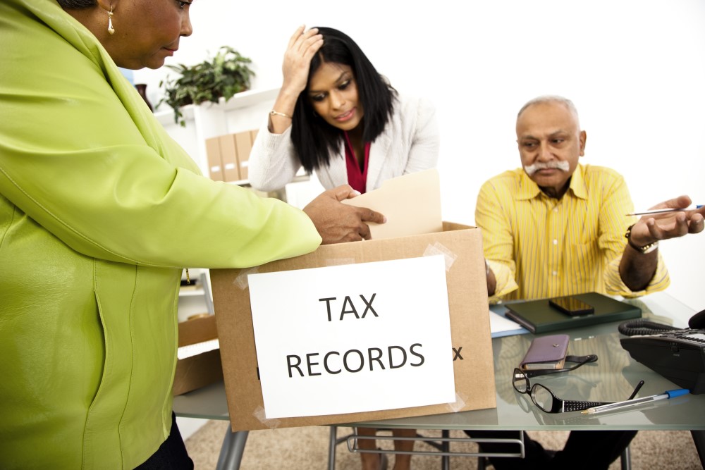 Three people look through a box labeled Tax Records