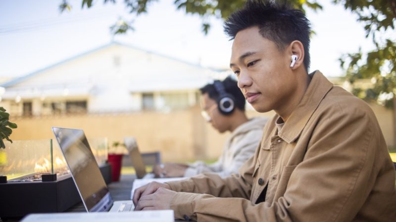 College students with headphones work on their laptops