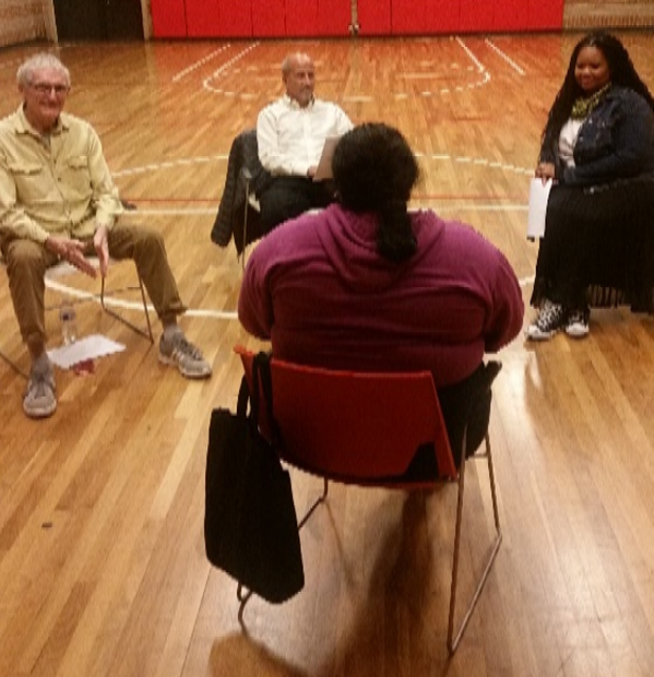 A mediator speaks with three people in a gymnasium