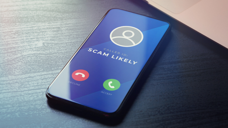 Photo of a cellphone ringing with caller ID showing the text "scam likely"
