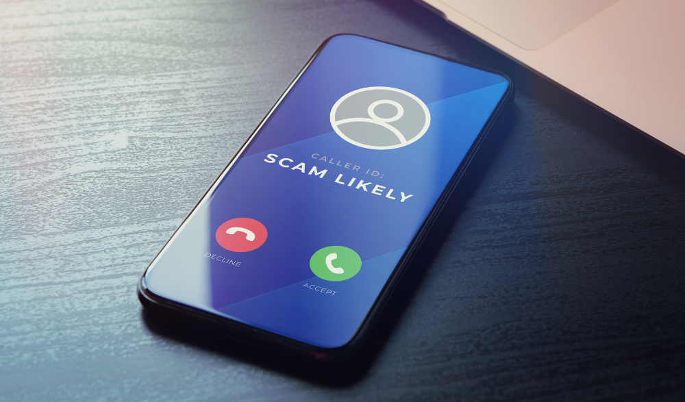 Photo of a cellphone ringing with caller ID showing the text "scam likely"