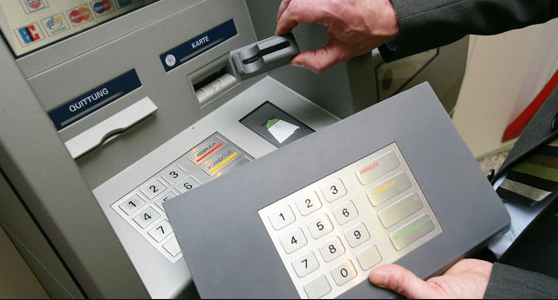 A keypad cover and card skimmer are placed on an ATM
