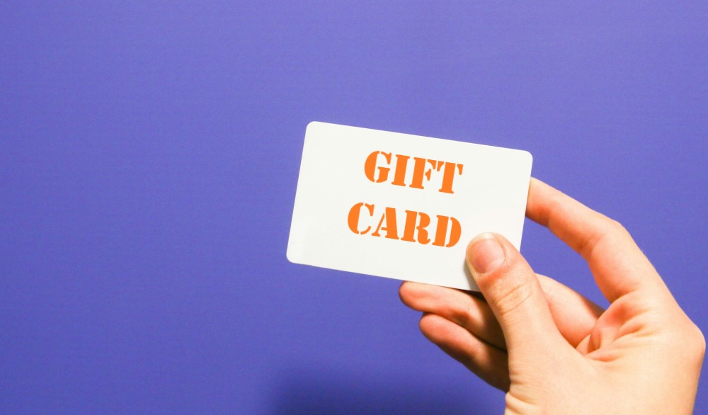 Hand holding a gift card that says "GIFT CARD"