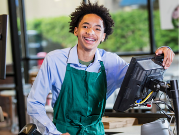 A young worker at a checkout stand smiles brightly